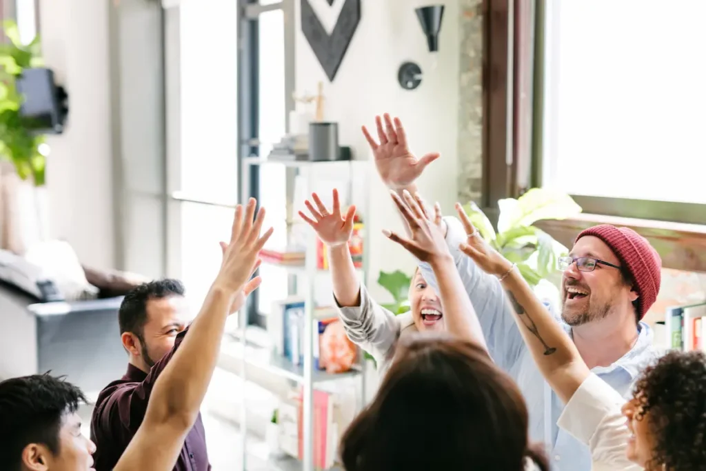 Empleados y gerentes de una misma empresa unidos y felices chocando sus manos tras una experiencia de teambuilding de Senttia
